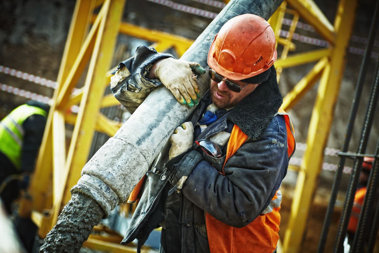 Trabajador de obra manipulando una manguera de concreto